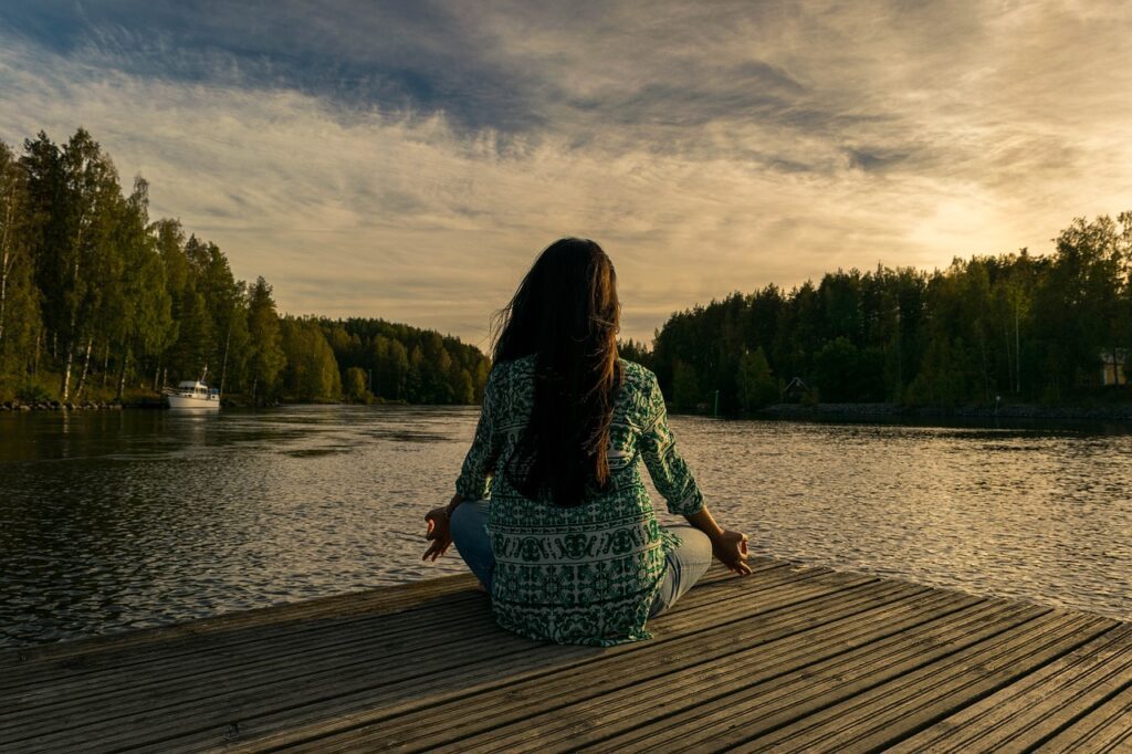 Woman meditating in front of a Lake.